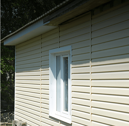 Side view of a beige house wall with a white window.