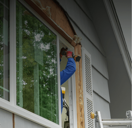 Person installing window on house exterior.